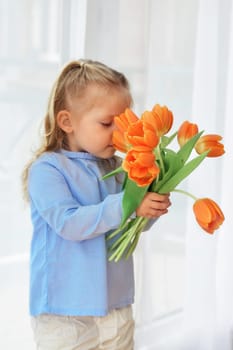 Girl holds and sniffing orange tulips Spring