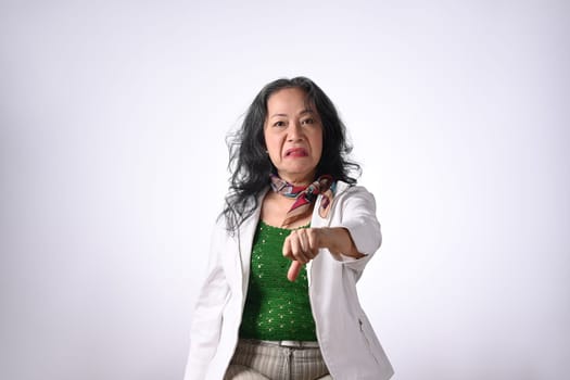 Upset senior woman showing thumbs down dislike gesture, expressing disapproval isolated on white background.