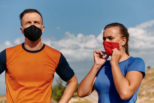 Couple running in nature at morning wearing protective face masks.