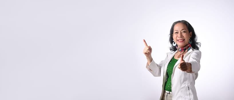 Smiling senior businesswoman pointing aside with copy space isolated on white background.