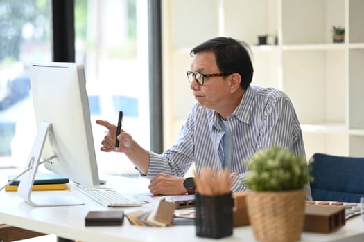 Concentrated senior male interior designer working on new design project at creative workplace.