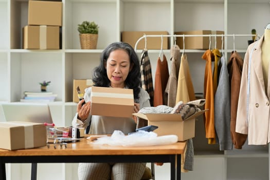 Middle age female entrepreneur checking order before sending to customers. E-commerce concept.