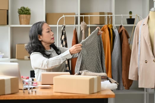 Senior woman small business owner packing product in cardboard box for delivery to customers.