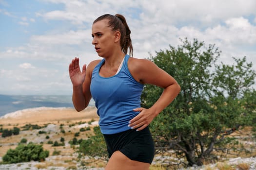 A determined female athlete runs through a forest trail at sunrise, surrounded by breathtaking natural beauty and vibrant greenery.