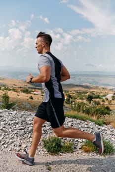 A muscular male athlete runs along a rugged mountain path at sunrise, surrounded by breathtaking rocky landscapes and natural beauty.