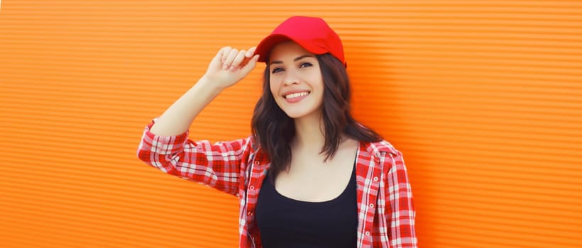 Summer portrait of happy smiling young woman posing in red baseball cap, casual clothes on city street