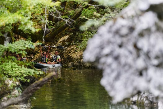 A young couple enjoying an idyllic kayak ride in the middle of a beautiful river surrounded by forest greenery.