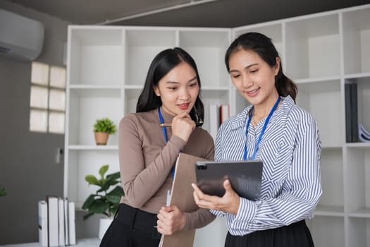 Two businesswomen discussing project with tablet in modern office. Concept of professional collaboration and teamwork.