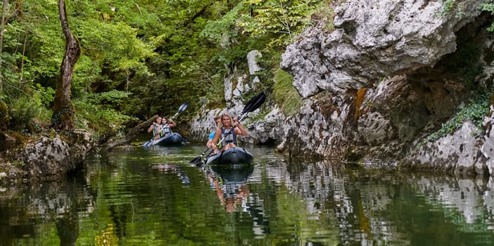 A group of friends enjoying having fun and kayaking while exploring the calm river, surrounding forest and large natural river canyons.