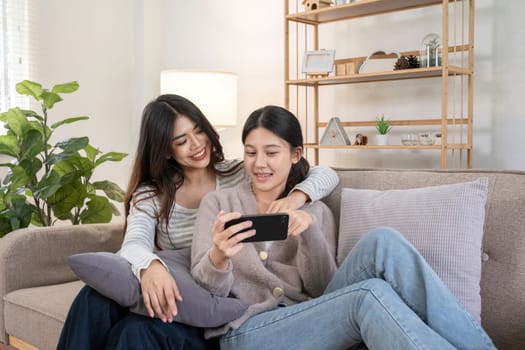Two young women watching video on smartphone together at home. Concept of friendship and technology.