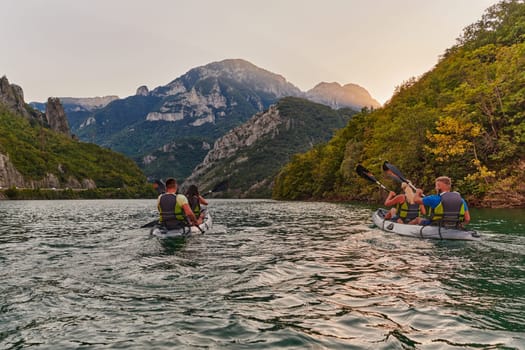 A group of friends enjoying fun and kayaking exploring the calm river, surrounding forest and large natural river canyons during an idyllic sunset