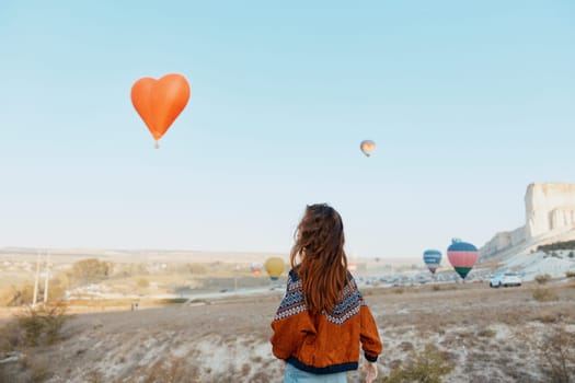 Stunning view of woman admiring colorful hot air balloons floating over the unique landscape of cappadocia, turkey