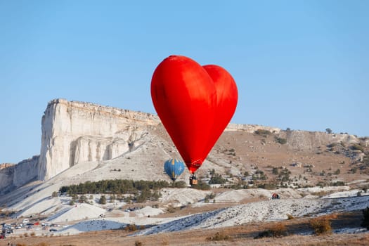 scenic love heart shaped balloon soaring over snowy mountain landscape