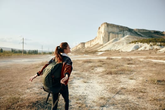 Serene woman standing in vast field with scenic mountain backdrop on sunny day