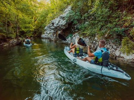 A group of friends enjoying having fun and kayaking while exploring the calm river, surrounding forest and large natural river canyons.