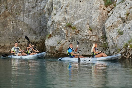 A group of friends enjoying having fun and kayaking while exploring the calm river, surrounding forest and large natural river canyons.