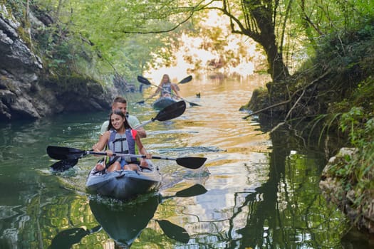 A group of friends enjoying having fun and kayaking while exploring the calm river, surrounding forest and large natural river canyons.