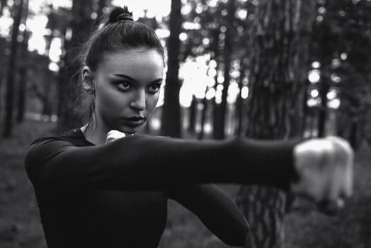 Black and white photo of a woman practicing martial arts in nature. film grain effect