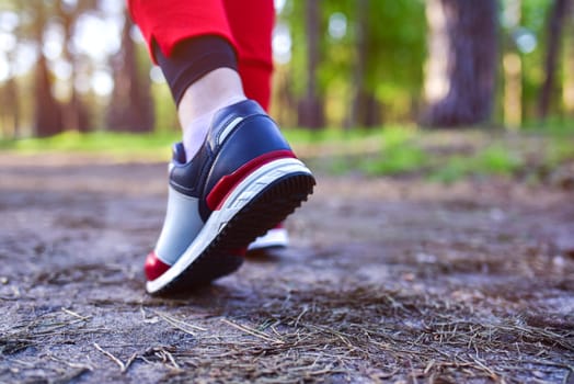 Women's feet in sneakers in the park. Running in nature.