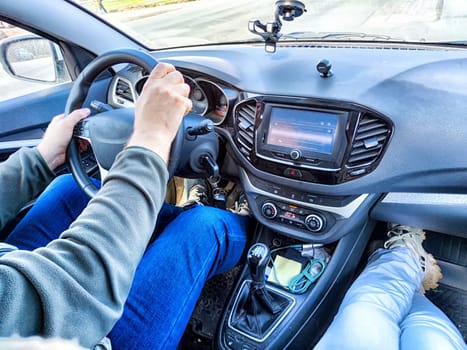 Man is driving with his hands on the steering wheel, while a female passenger sits beside him