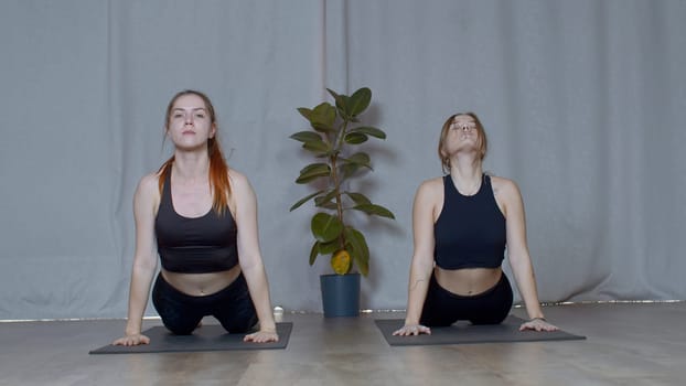 Athletic young women doing exercisizes for the spine stretching. Media. Concept of inner peace and no stress