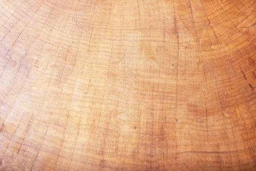 A detailed view of a wooden surface displaying a textured grain. The colors include shades of brown, beige, and peach. The pattern suggests a hardwood material with a wood stain finish