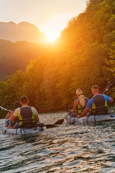 A group of friends enjoying fun and kayaking exploring the calm river, surrounding forest and large natural river canyons during an idyllic sunset