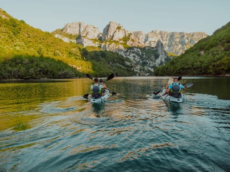 A group of friends enjoying having fun and kayaking while exploring the calm river, surrounding forest and large natural river canyons.