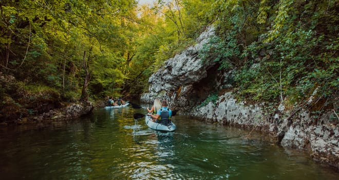 A group of friends enjoying having fun and kayaking while exploring the calm river, surrounding forest and large natural river canyons.