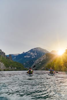 A group of friends enjoying fun and kayaking exploring the calm river, surrounding forest and large natural river canyons during an idyllic sunset