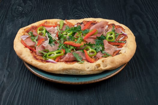 Italian Pizza on plate with jamon slices, pepper and fresh arugula leaves on top