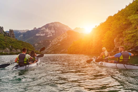 A group of friends enjoying fun and kayaking exploring the calm river, surrounding forest and large natural river canyons during an idyllic sunset