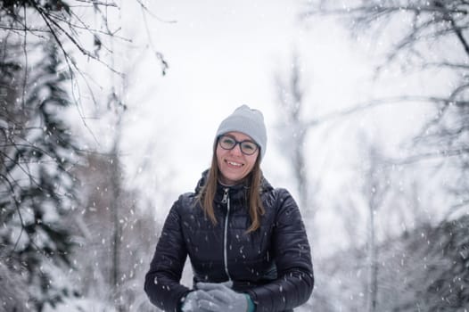 Woman in winter jacket walking in snowy winter forest, snowy winter day