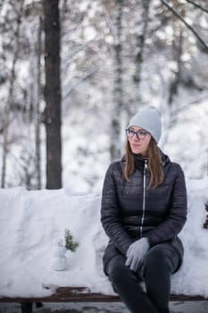 Woman in winter jacket walking in snowy winter forest, snowy winter day