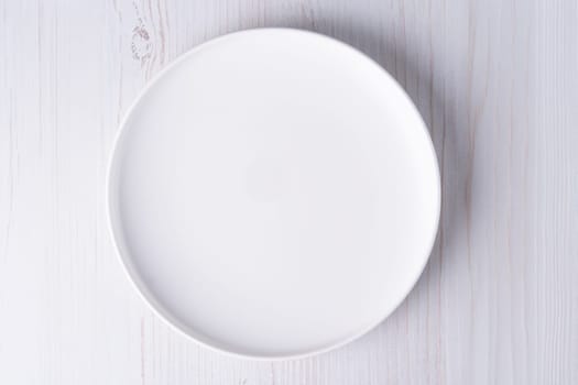 empty plate on white wooden table, top view.