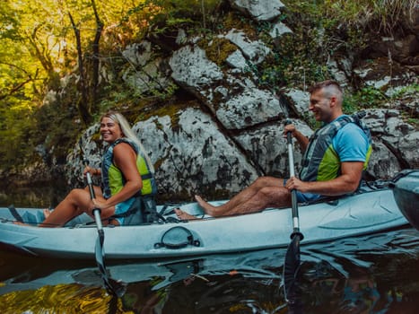 A young couple enjoying an idyllic kayak ride in the middle of a beautiful river surrounded by forest greenery.