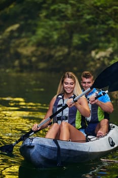 A young couple enjoying an idyllic kayak ride in the middle of a beautiful river surrounded by forest greenery.