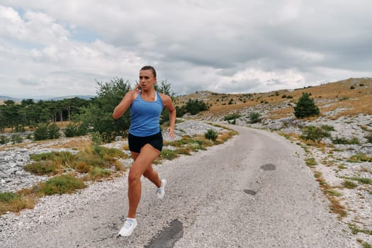 A determined female athlete runs through a forest trail at sunrise, surrounded by breathtaking natural beauty and vibrant greenery.