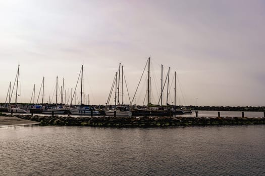 Sea pier with boats and yachts at sunset. Bornholm, Denmark - May 28, 2024. High quality photo