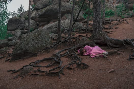 Woman in raincoat in the taiga forest and rocks of the Stolby nature reserve park, Krasnoyarsk, Russia