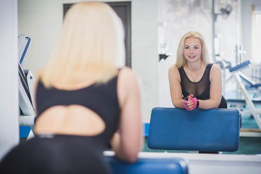 Beautiful blonde in leggings resting in the gym.