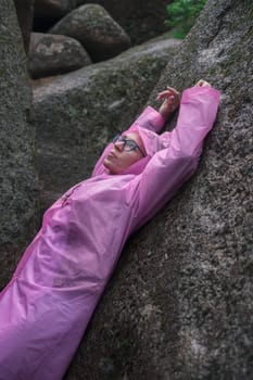 Woman in the raincoat the taiga forest and rocks of the Stolby nature reserve park, Krasnoyarsk, Russia