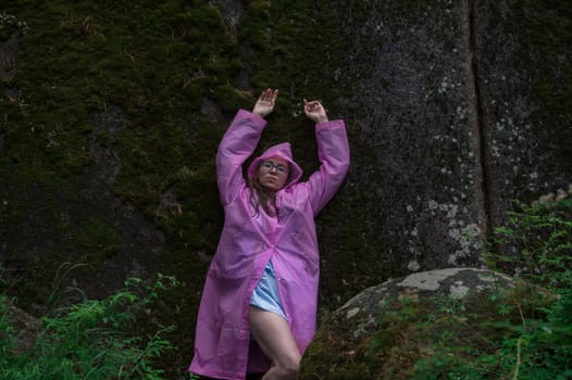 Woman in the raincoat the taiga forest and rocks of the Stolby nature reserve park, Krasnoyarsk, Russia