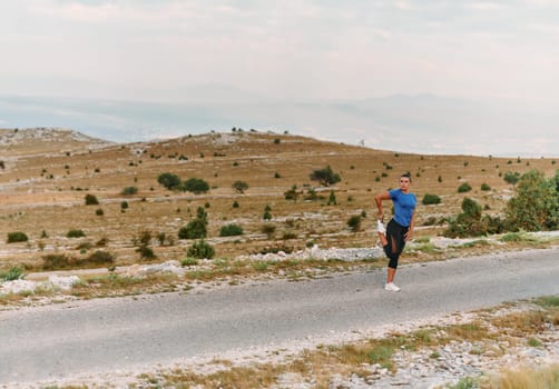 A determined female athlete stretches her muscles after a strenuous run through rugged mountain terrain, surrounded by breathtaking rocky landscapes.