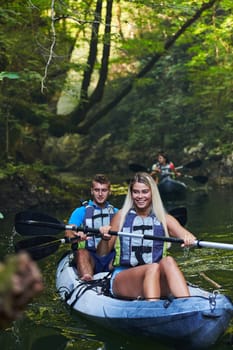 A group of friends enjoying having fun and kayaking while exploring the calm river, surrounding forest and large natural river canyons.