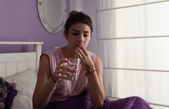 Young woman taking pills for back pain. Tiredness and stress.