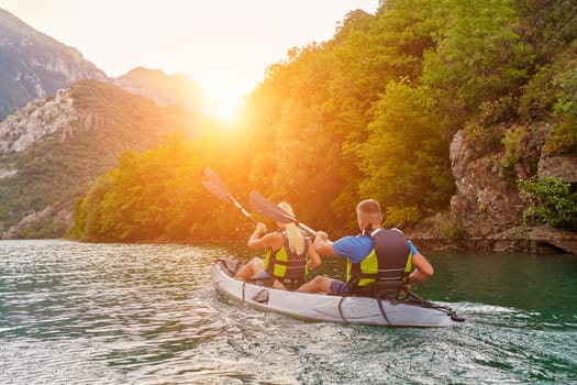 A group of friends enjoying fun and kayaking exploring the calm river, surrounding forest and large natural river canyons during an idyllic sunset