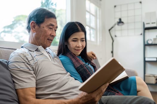 senior married couple enjoying quality time reading books together on the couch.