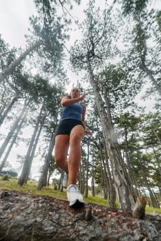 A brave woman traverses through the forest, fearlessly leaping over dangerous obstacles with determination and agility, showcasing her adventurous spirit and athletic prowess.