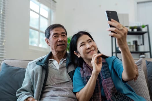 A man and woman are sitting on a couch, both looking at a cell phone. They seem to be enjoying their time together